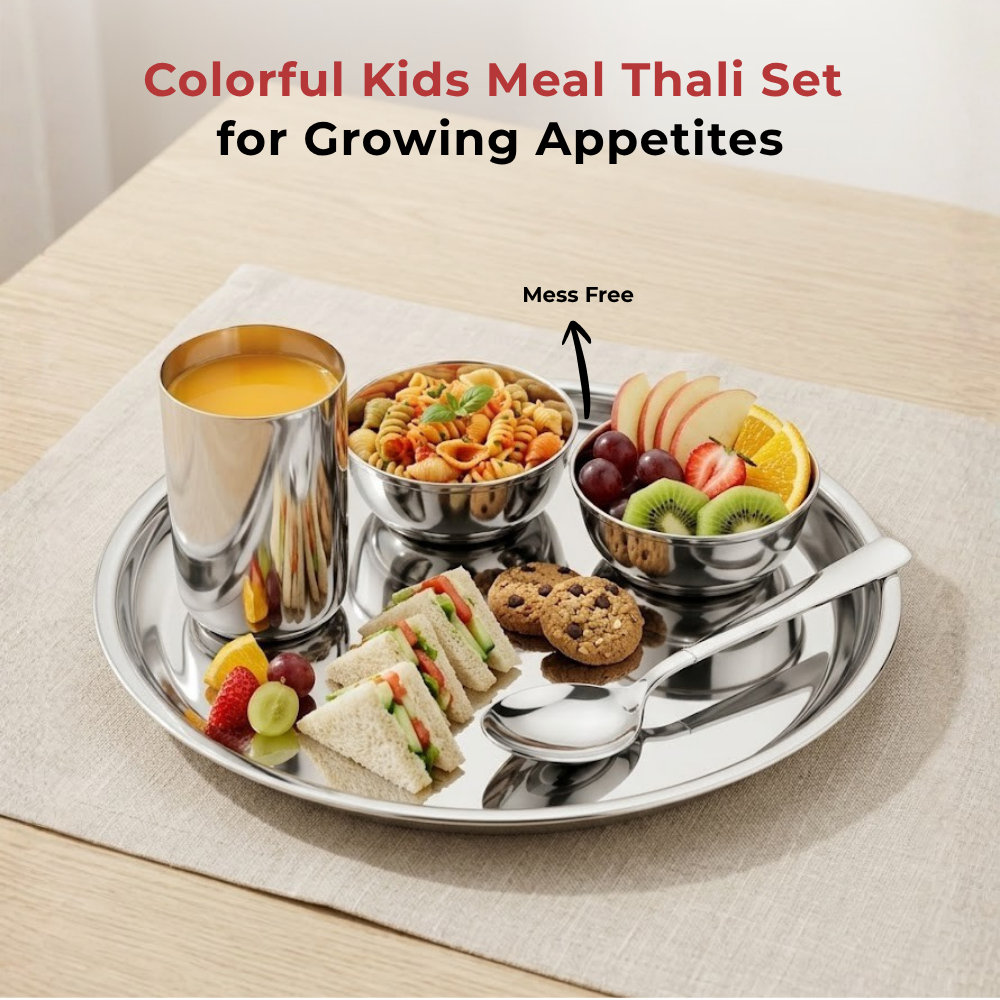 A stainless steel kids' meal set on a beige placemat, featuring a round tray with a cup of orange juice, pasta bowl, fruit bowl, sandwich halves, cookies, and a spoon. Text at the top reads 'Colorful Kids Meal Thali Set for Growing Appetites' with 'Mess Free' and an arrow pointing to the tray.